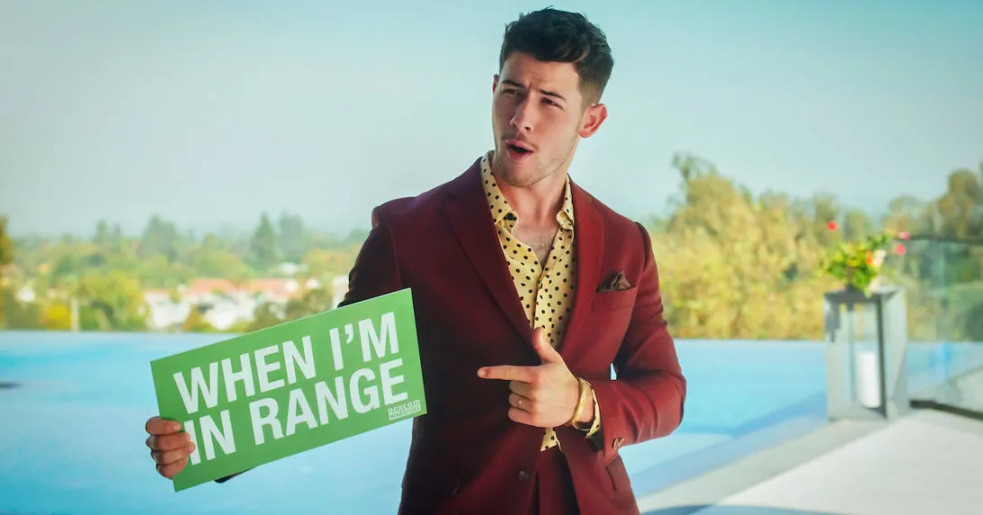 Nick Jonas pointing to a green sign that says "When I'm in range"