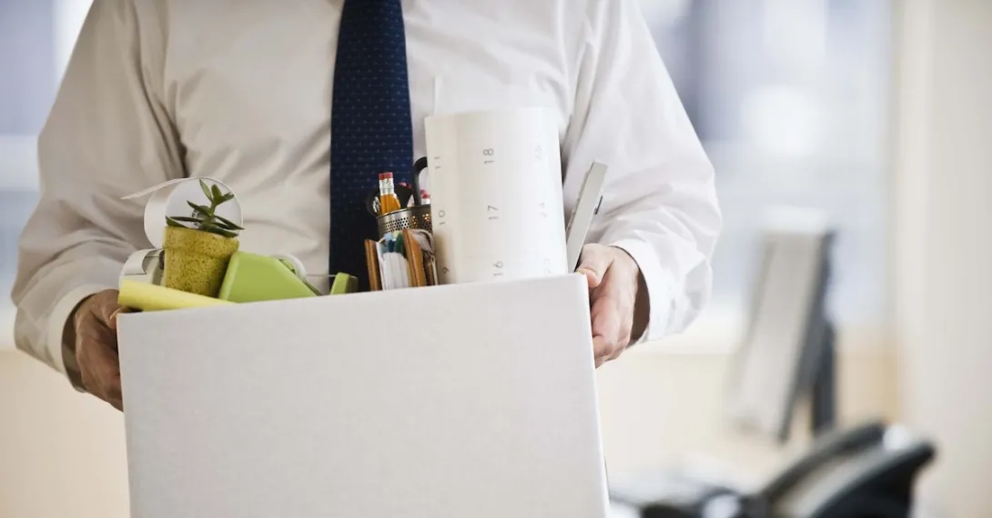 A man leaving an office carrying a box of his belongings. A man leaving an office carrying a box of his belongings.