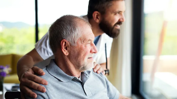 adult caregiver and person look out a window