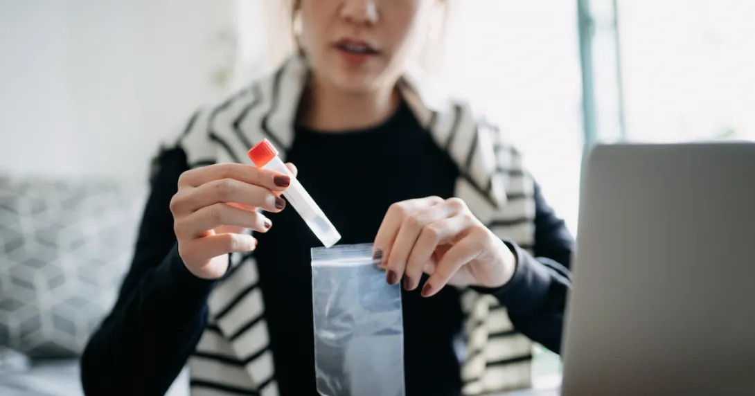 A person at home puts a lab sample into a bag for shipping A person at home puts a lab sample into a bag for shipping
