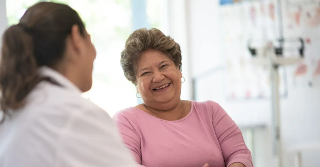 A medical professional talking to a laughing patient A medical professional talking to a laughing patient