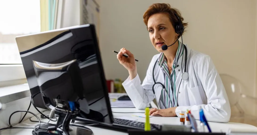 A doctor wearing a headset and working on a computer A doctor wearing a headset and working on a computer