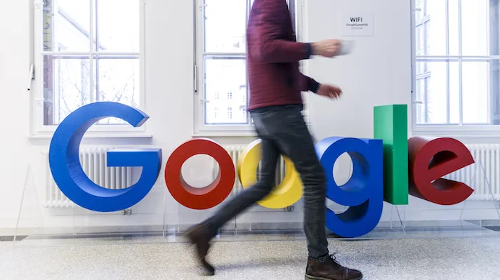 A man walks by a Google logo A man walks by a Google logo