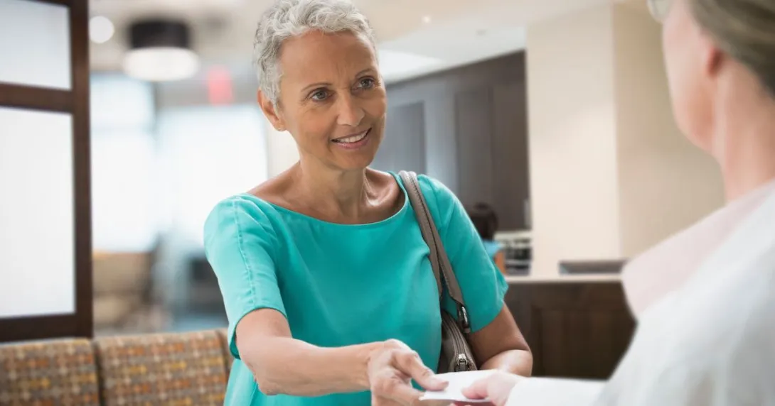 A woman handing her insurance card to a healthcare worker A woman handing her insurance card to a healthcare worker