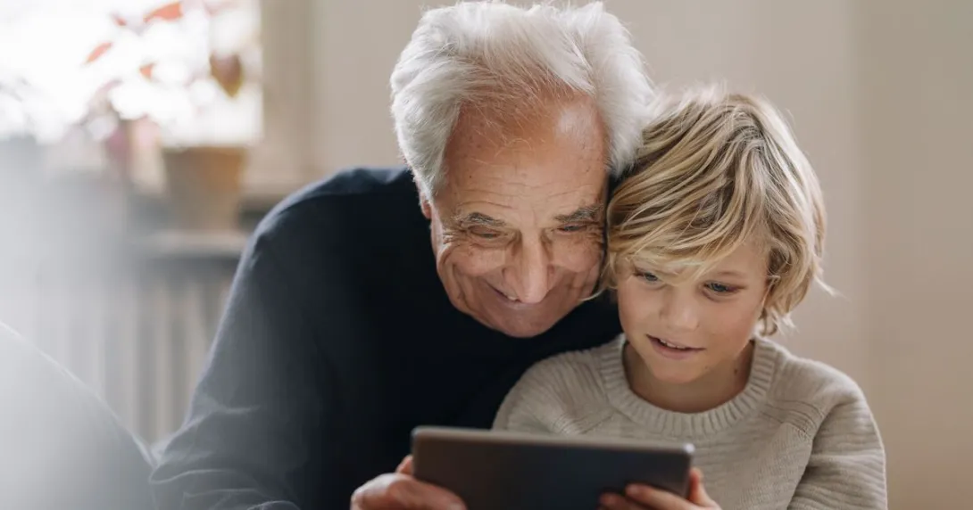 An older man and a child using a tablet together An older man and a child using a tablet together