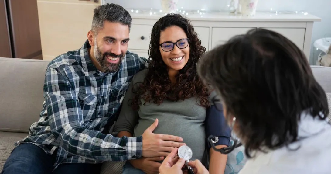 A doctor visits a pregnant patient and partner at home A doctor visits a pregnant patient and partner at home