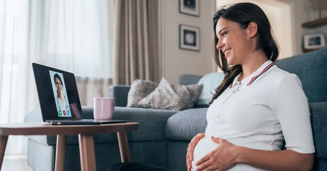 A pregnant person talking to a provider through a video chat on her laptop. A pregnant person talking to a provider through a video chat on her laptop.