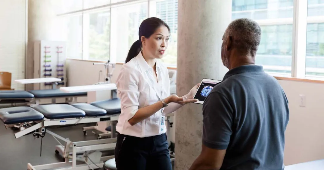 A medical professional uses a digital tablet to explain brain injury and recovery to a person after his stroke. A medical professional uses a digital tablet to explain brain injury and recovery to a person after his stroke.