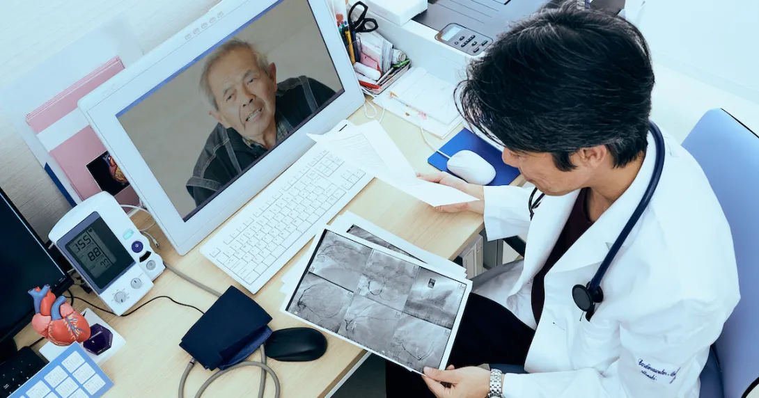 A provider holding imaging results talking to a patient via telehealth A provider holding imaging results talking to a patient via telehealth