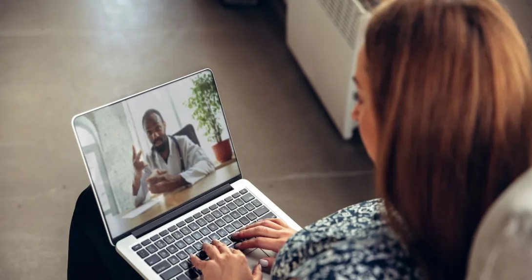 A woman talking to a doctor via telehealth using her laptop A woman talking to a doctor via telehealth using her laptop