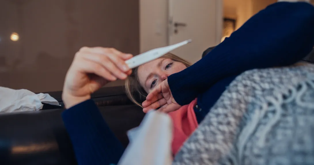 A sick woman looking a thermometer A sick woman looking a thermometer