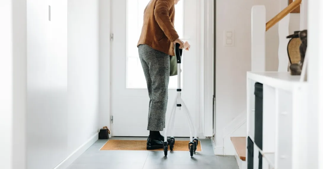 A senior adult using a walker opening a door