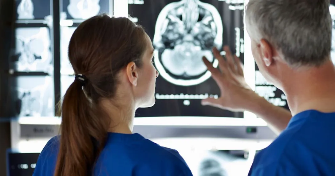 Two healthcare providers looking at a diagnostic image of a brain scan