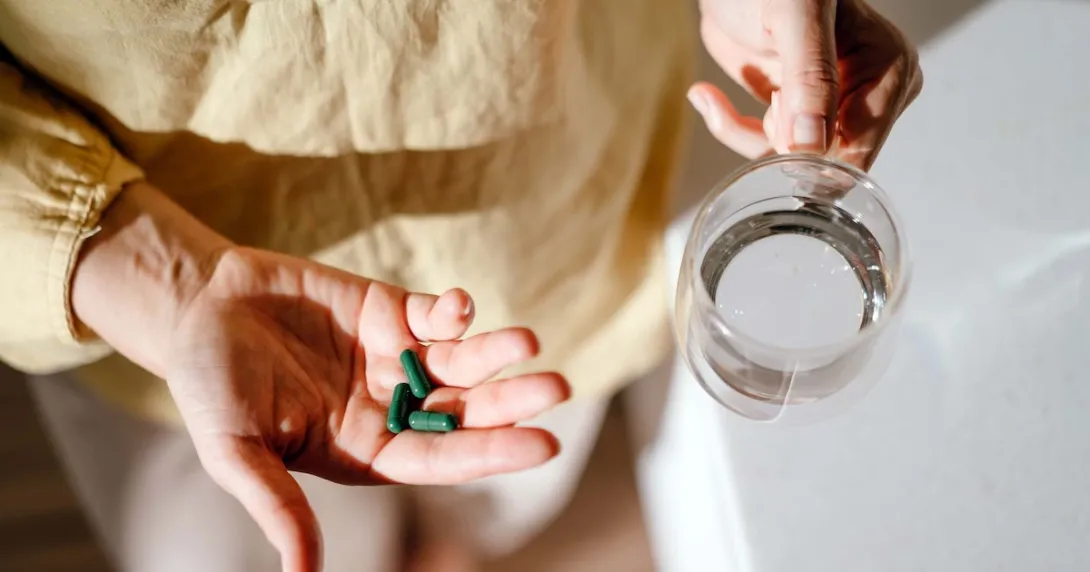 Person holding green pills in their hand