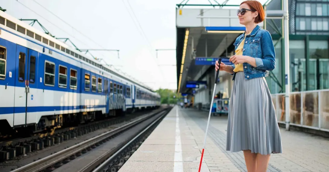 Blind person standing at a train station