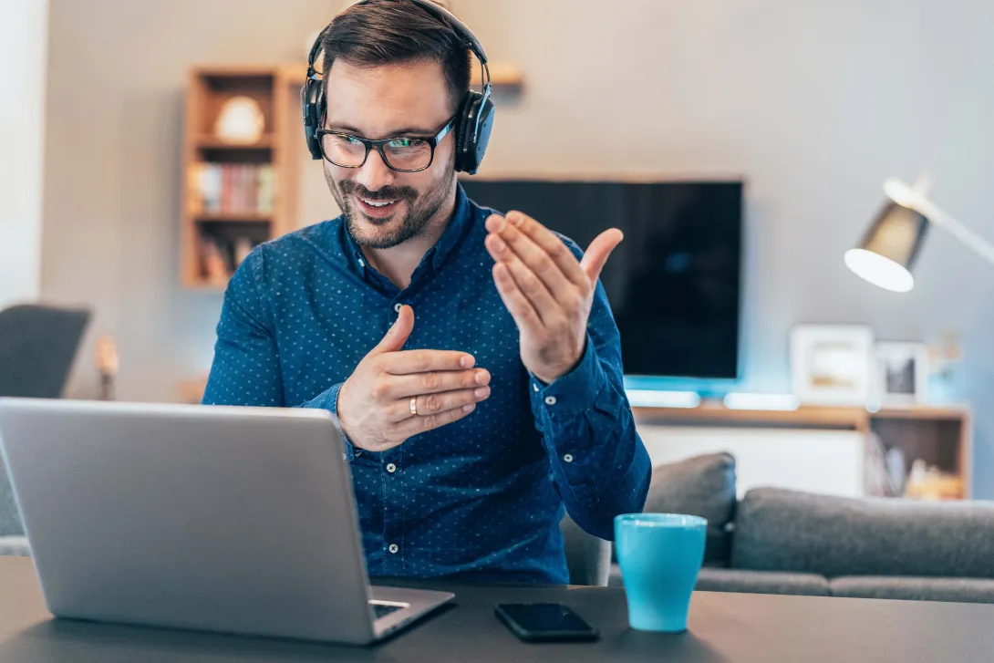 Worker with headphones conducting meeting on laptop