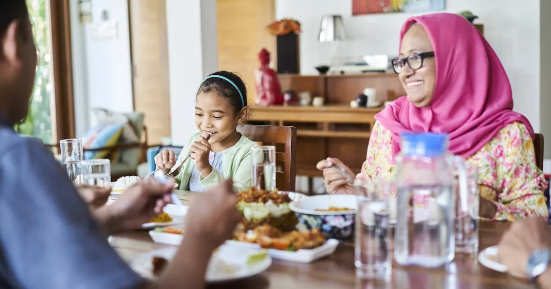 People sitting around a dinner table with food on it