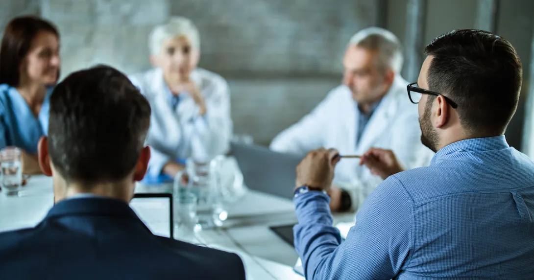 Five people sitting around a table speaking with each other