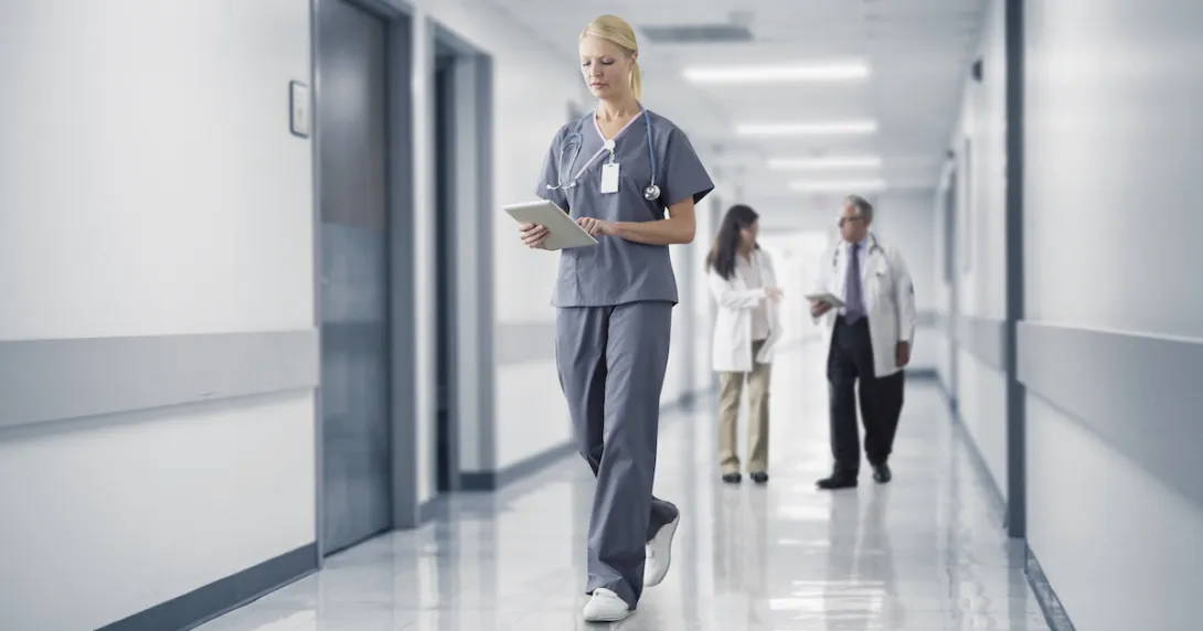 Healthcare provider walking through a hallway with two other healthcare providers standing behind them