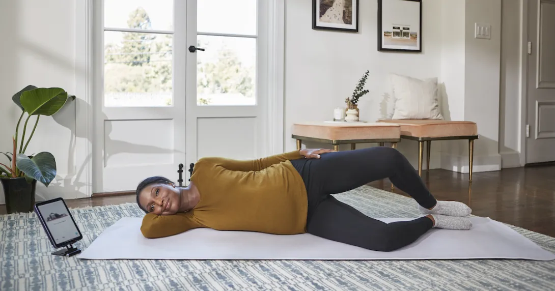 A woman doing a pelvic floor exercise while using Hinge's app on a tablet