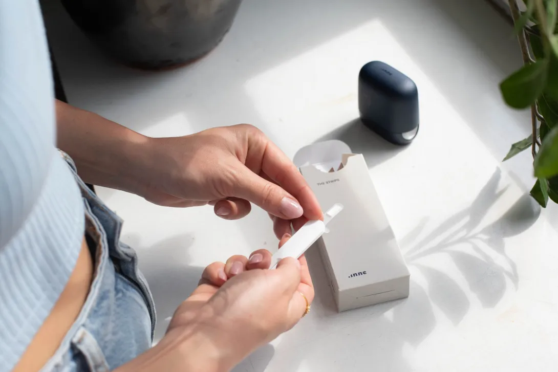 Person holds a test strip. Healum, NHS, women's health