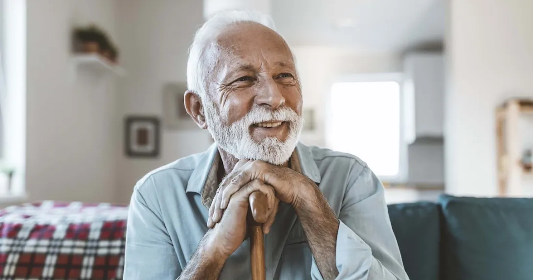 Person sitting on their ouch while holding their cane