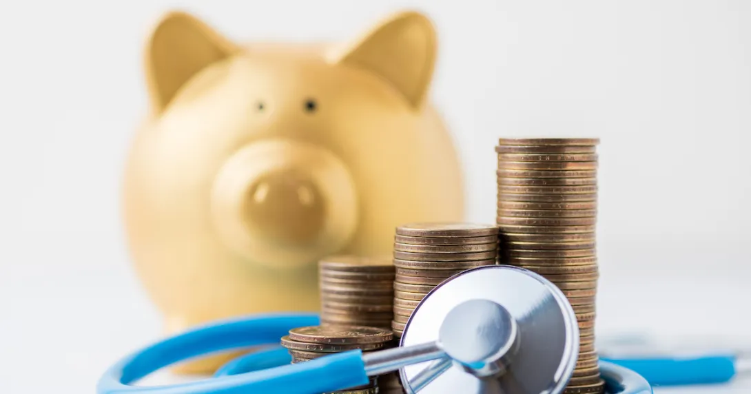 A piggy bank next to a stethoscope and a pile of coins.