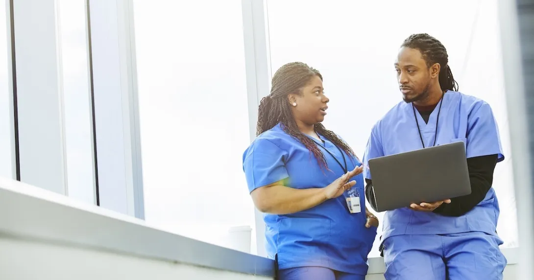 Healthcare professionals conferring while using a laptop computer