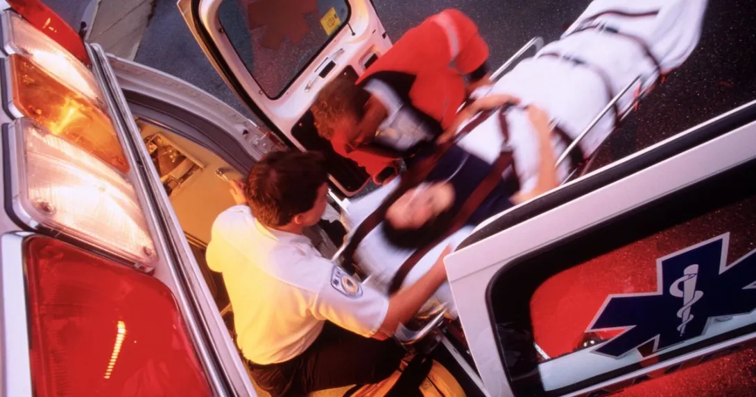 Paramedics rolling a patient onto an ambulance.