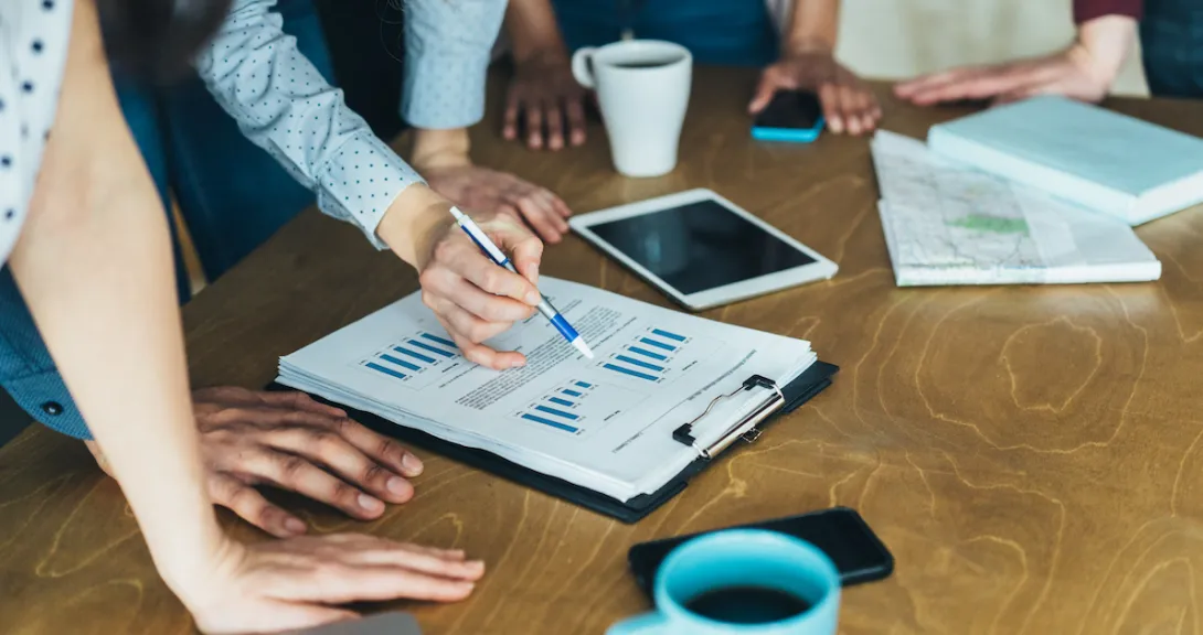 A close-up of a group of workers looking at a paper with financial charts