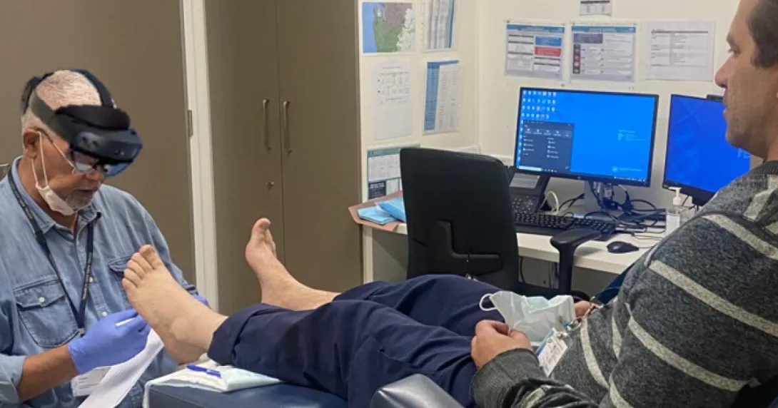 A clinician demonstrating the use of mixed-reality glasses for remote assessment of a foot wound