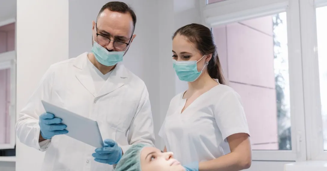 Dentist and his assistant using tablet in the process of treating teeth of patient
