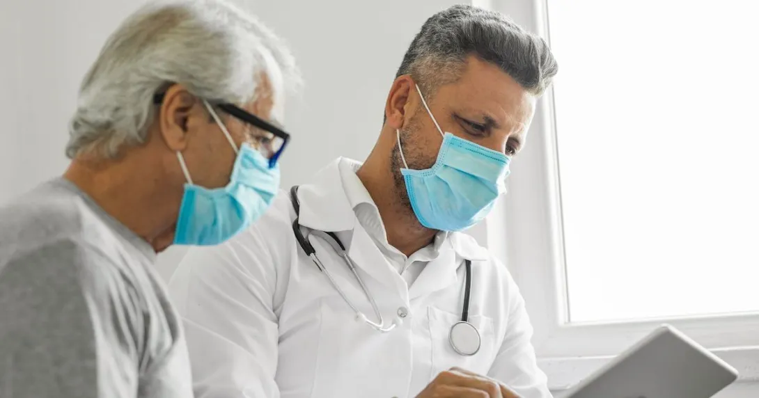 A medical professional and a patient talking to another provider using a tablet.