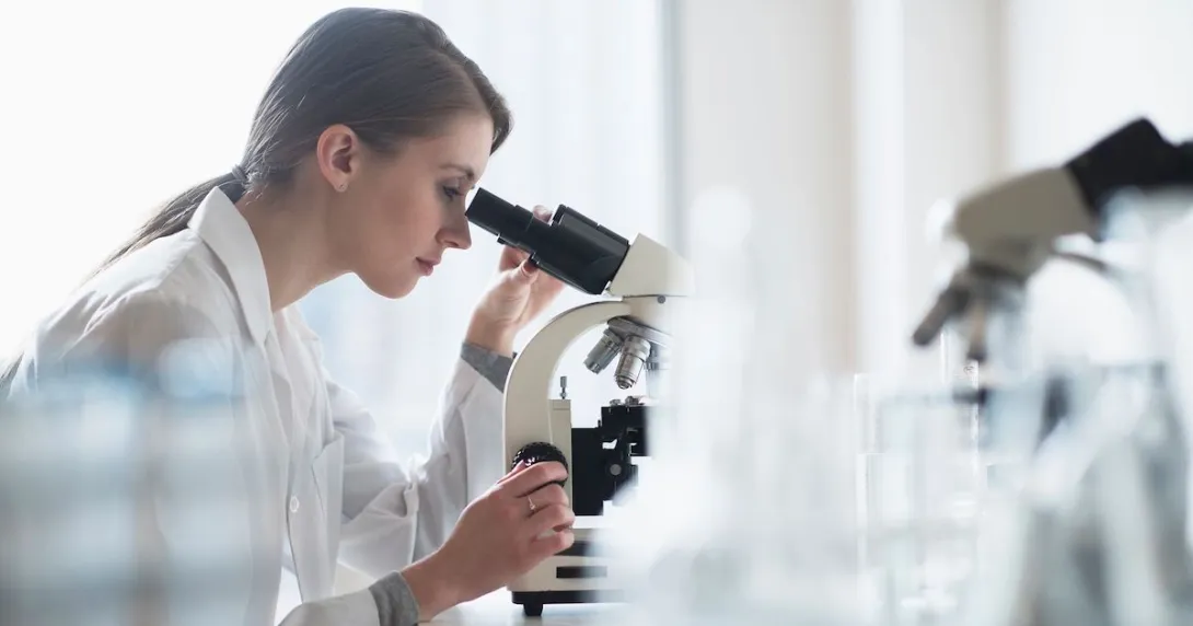 A researcher using a microscope in a lab