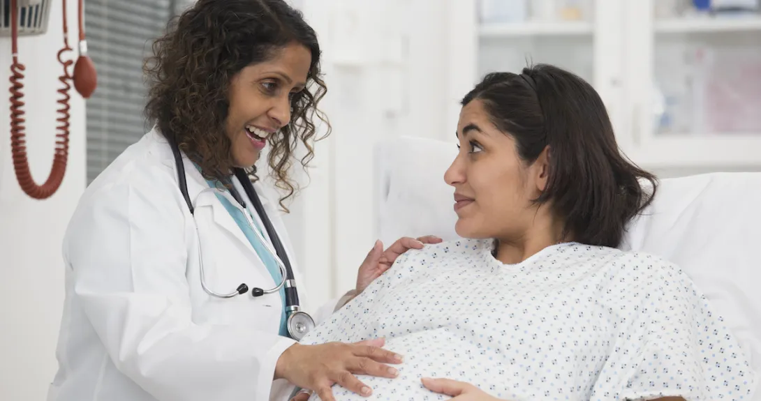 A pregnant woman talking with a doctor in a hospital.