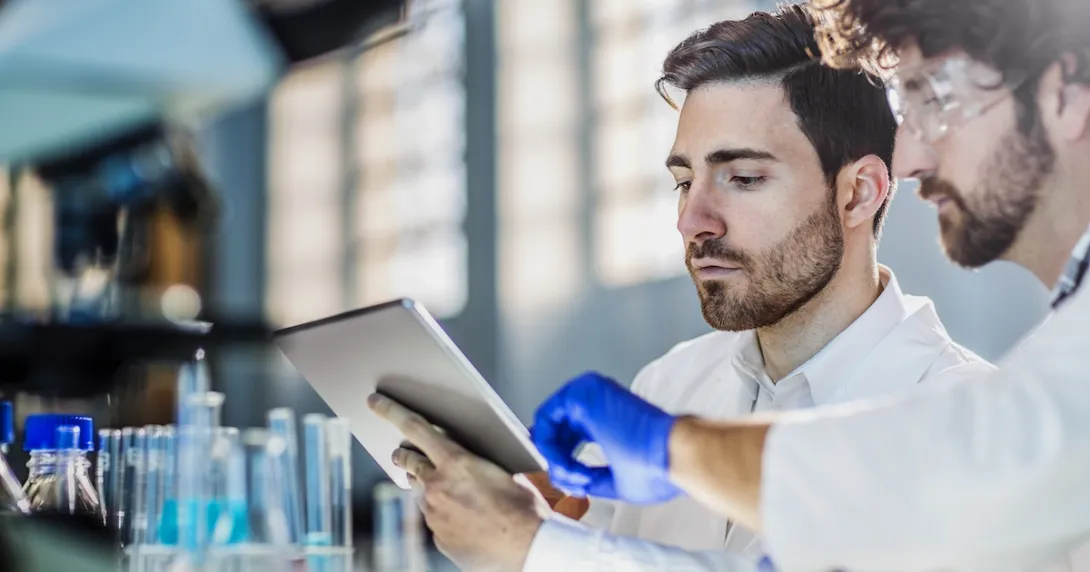 Two scientists in a lab looking at a tablet