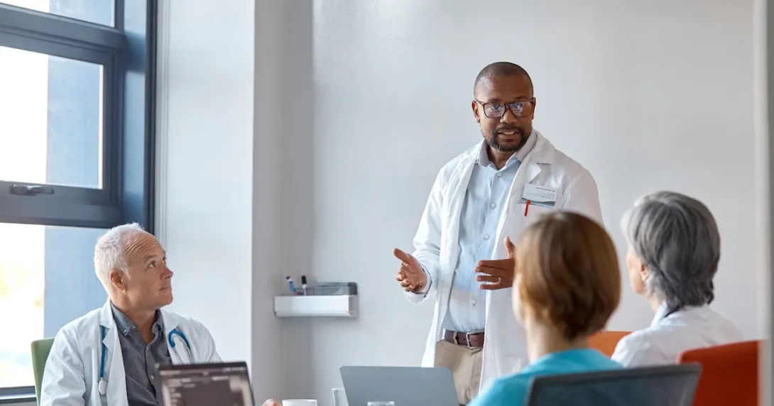 Healthcare provider standing in front of three other people in a meeting room