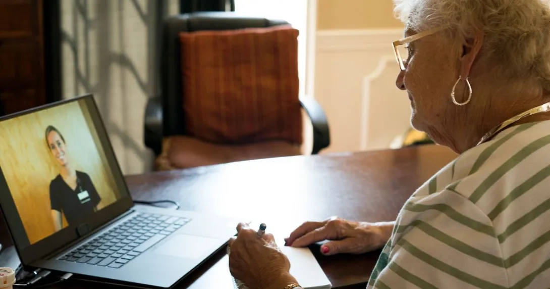 Person sitting in front of a computer while talking to a virtual healthcare provider