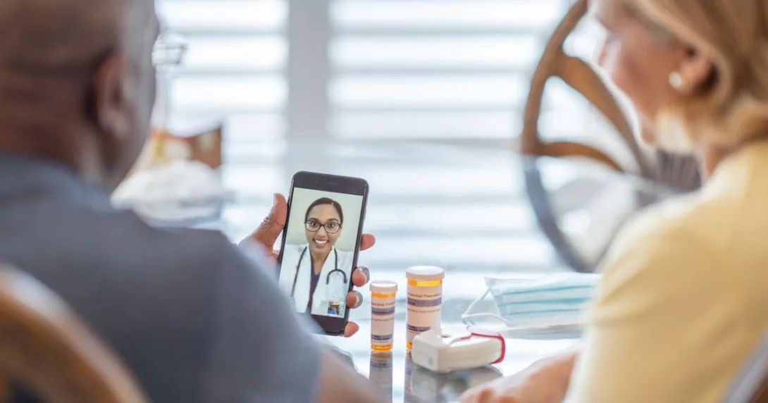 Two people on a telehealth call with medication on the table