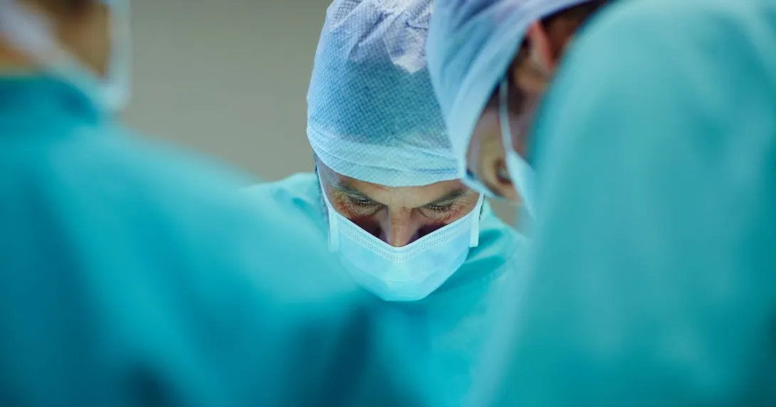 Surgeons in scrubs looking down at a patient in the operating room