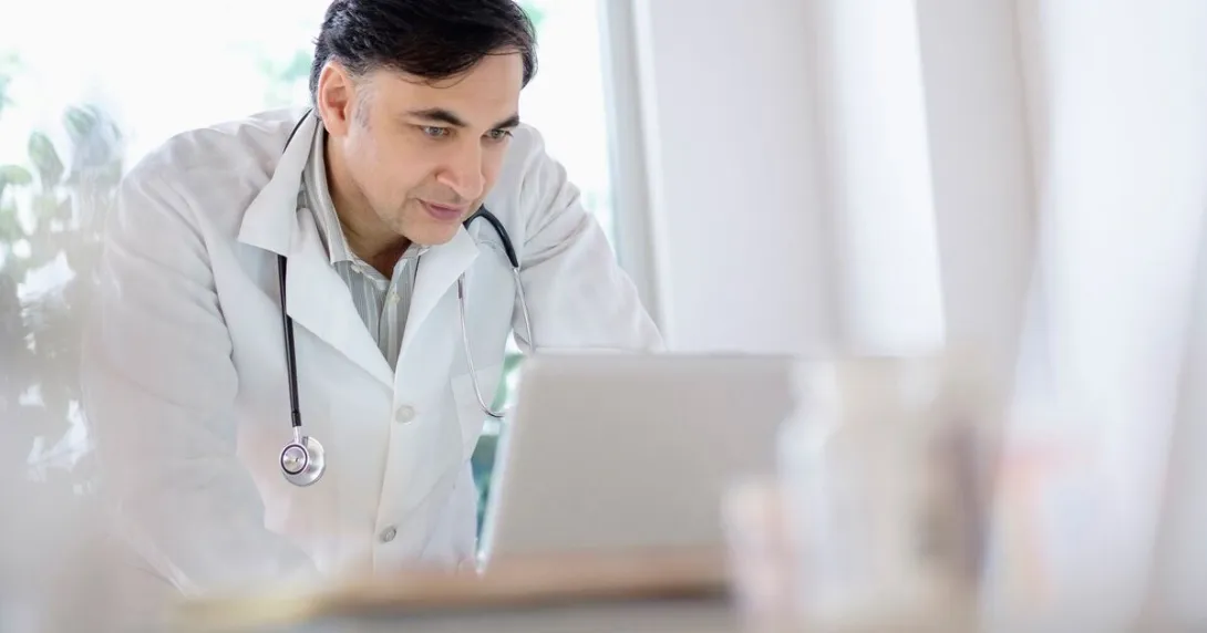 A doctor using a laptop to write referrals