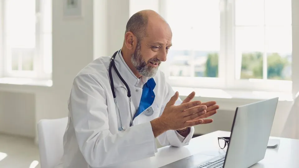 Healthcare provider sitting at a desk while looking at a laptop