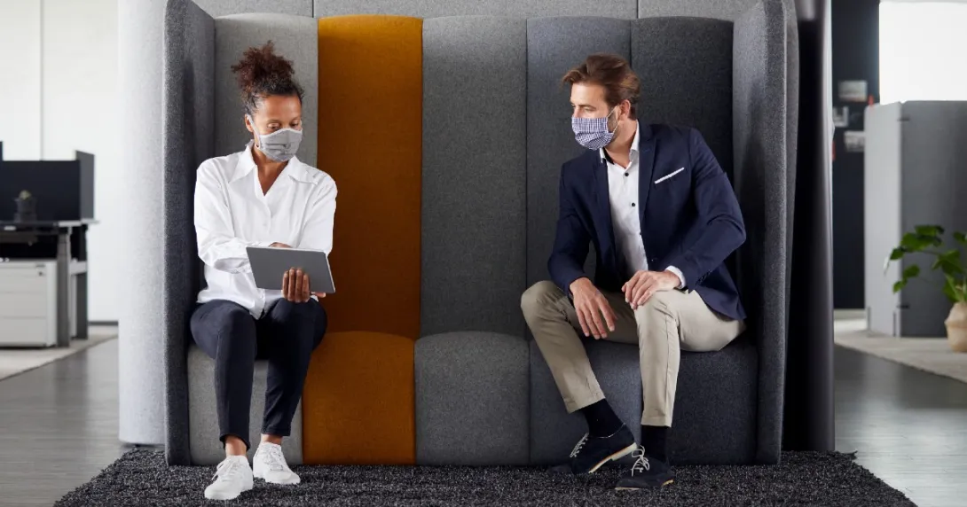 Woker in mask showing tablet to other worker in mask